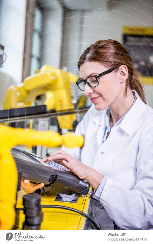 Woman using device in factory with industrial robots factories engineer female engineer engineers female engineers Robot industry male profession business