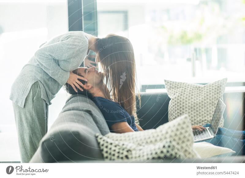 Young couple in love at home kissing kisses twosomes partnership couples people persons human being humans human beings couch settee sofa sofas couches settees
