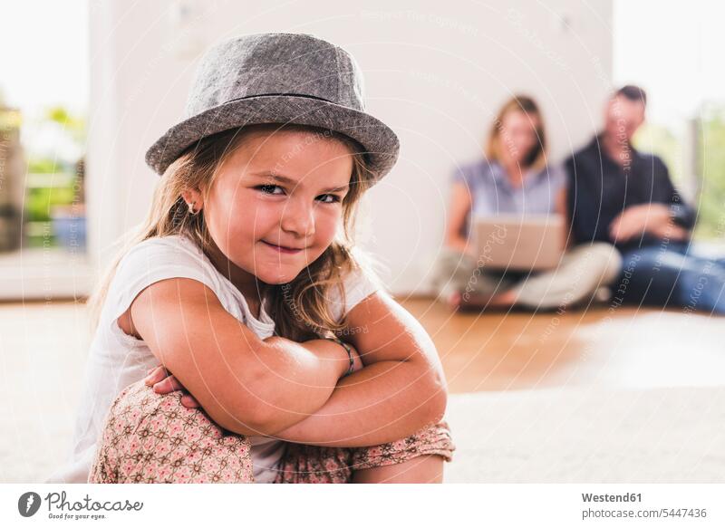 Little girl with hat, parents using laptop in background hats confidence confident wireless Wireless Connection Wireless Technology Wireless Communication