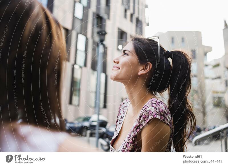 Smiling young woman in the city looking up females women smiling smile Adults grown-ups grownups adult people persons human being humans human beings beautiful