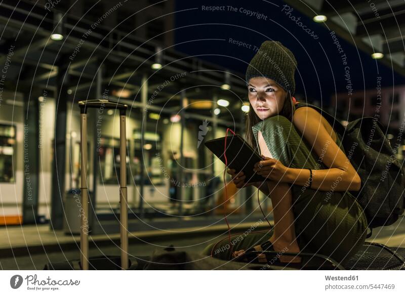 Portrait of young woman with headphones and tablet waiting at station by night females women Adults grown-ups grownups adult people persons human being humans