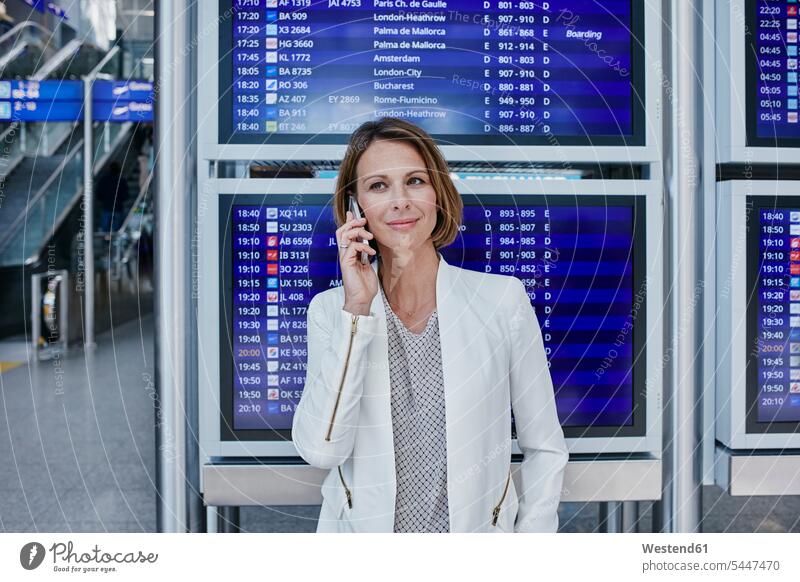 Businesswoman with cell phone at timetable at the airport mobile phone mobiles mobile phones Cellphone cell phones businesswoman businesswomen business woman