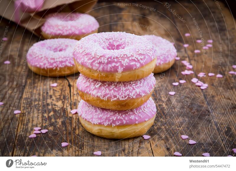 Stack of Doughnuts with pink icing and sugar granules on wood on top of sugar icing frosting baking decor sweet Sugary sweets Rosy streusel wooden magenta