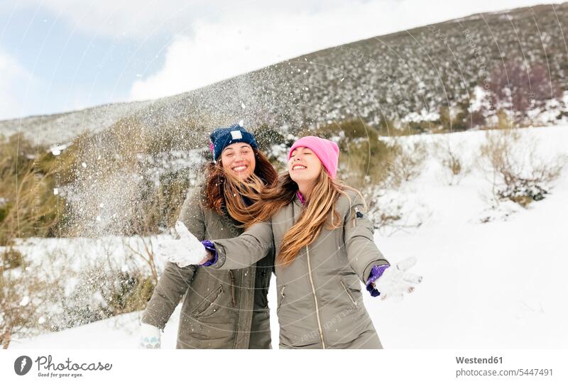 Two friends having fun in the snow friendship female friends throwing laughing Laughter winter hibernal mate weather positive Emotion Feeling Feelings