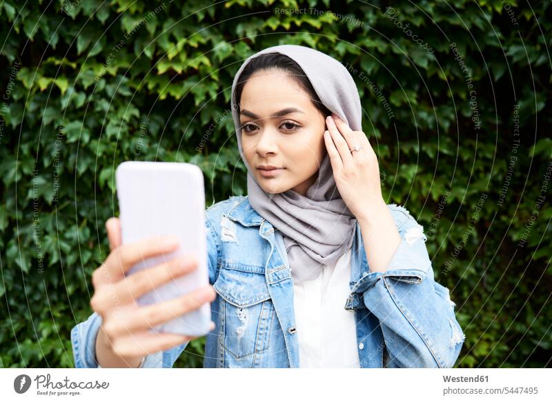 Young woman looking at her phone screen wearing hijab headscarf head scarf head scarves Head Scarf head cloths headscarves Muslim mobile phone mobiles