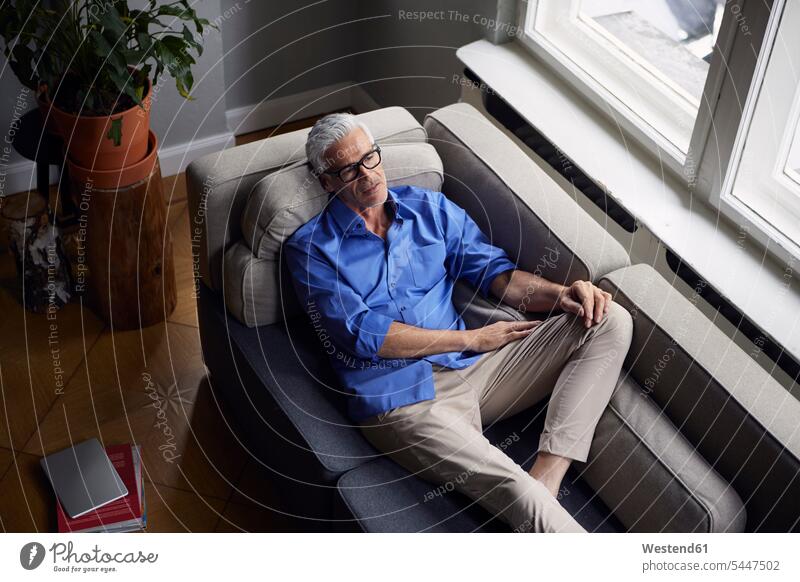 Pensive mature man on couch at home men males settee sofa sofas couches settees Adults grown-ups grownups adult people persons human being humans human beings