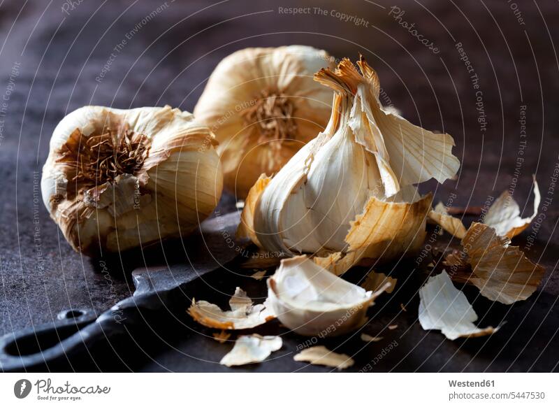 Smoked garlic on rusty ground knife knives healthy eating nutrition wrought iron wrought-iron smoked aroma flavour aromatic spice spices peel peels garlic clove