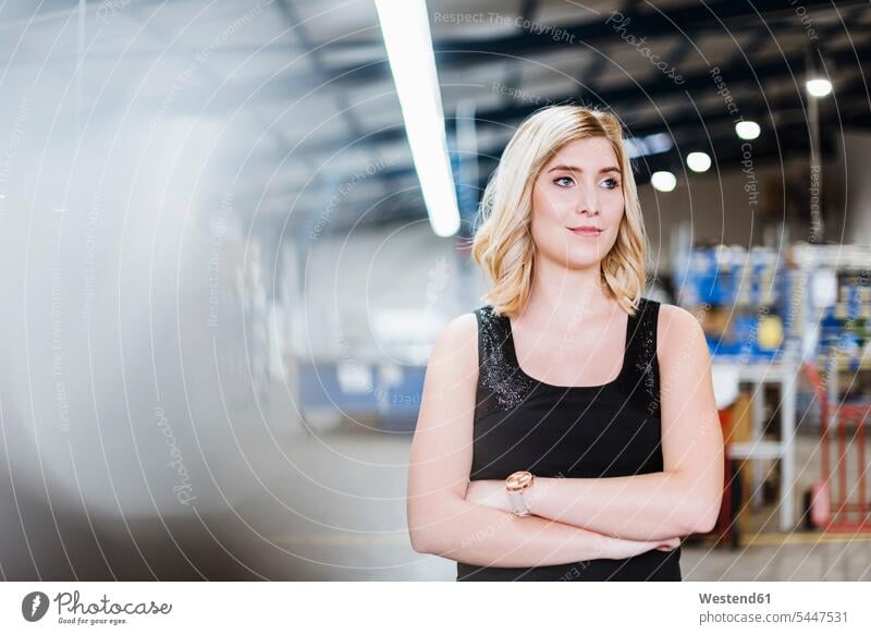Blonde businesswoman standing on shop floor with arms crossed, portrait businesswomen business woman business women blond blond hair blonde hair manager