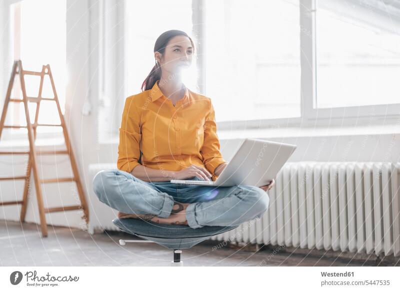 Yung woman sitting in her new flat with a laptop females women young ladder ladders moving house move Moving Home Laptop Computers laptops notebook Adults