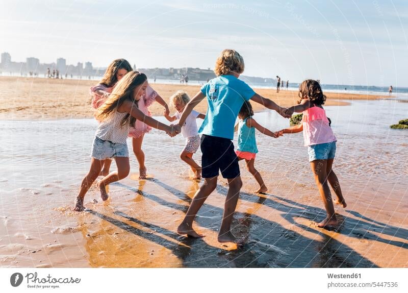 Group of six children playing ring-a-ring-a-roses on the beach Ring-Around-The-Rosy beaches friends friendship group of people groups of people kid kids persons