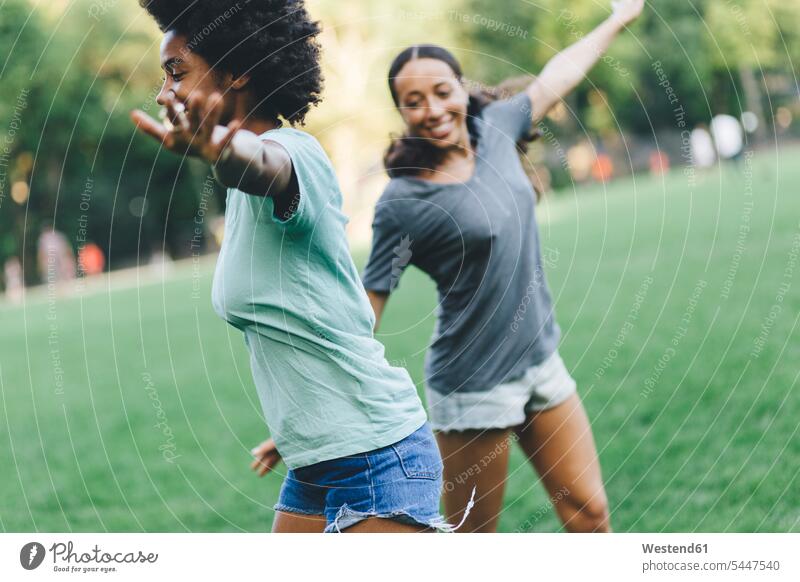 Two best friends having fun together in the park at evening parks female friends playing mate friendship walking going African-American Ethnicity Afro-American