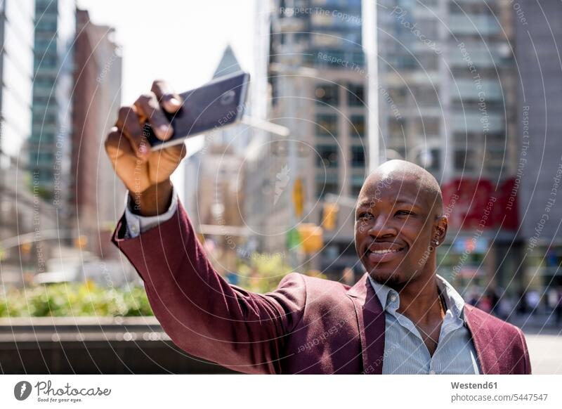 USA, New York City, Manhattan, stylish businessman taking selfie with smartphone portrait portraits Businessman Business man Businessmen Business men Selfie