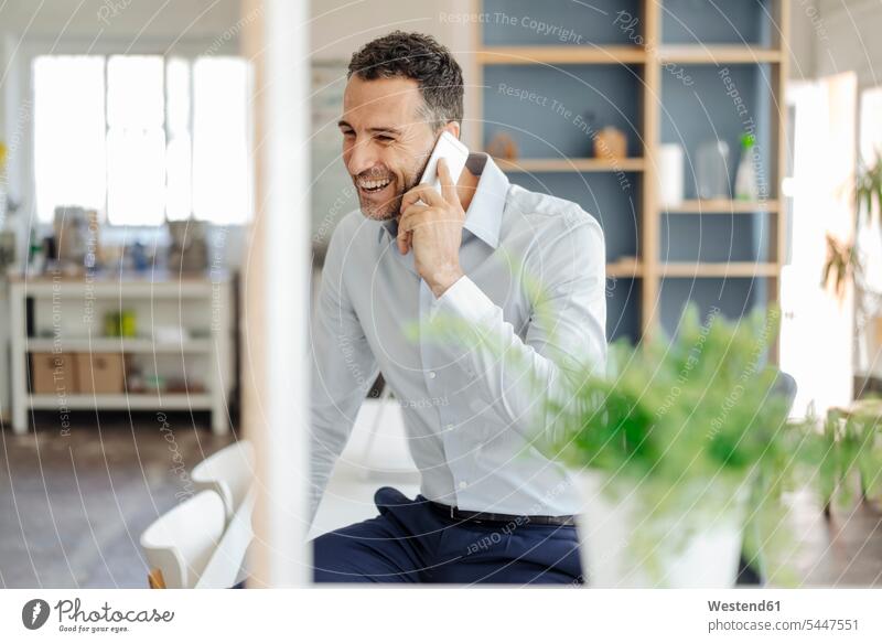 Happy businessman in office on cell phone mobile phone mobiles mobile phones Cellphone cell phones laughing Laughter Businessman Business man Businessmen
