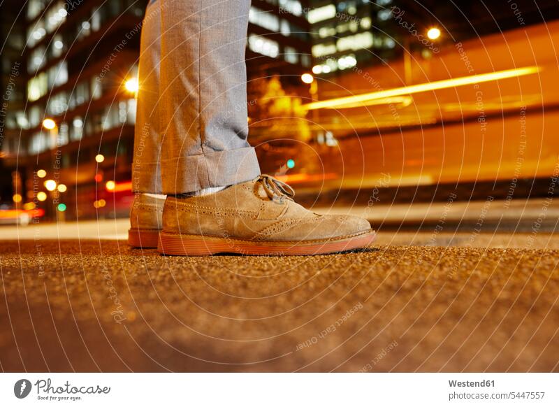 Feet of businessman standing at roadside in the city at night, close-up Businessman Business man Businessmen Business men town cities towns foot human foot