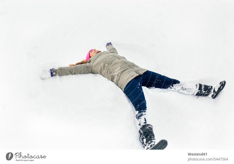 Young woman making a snow angel laughing Laughter winter hibernal positive Emotion Feeling Feelings Sentiments Emotions emotional weather caucasian