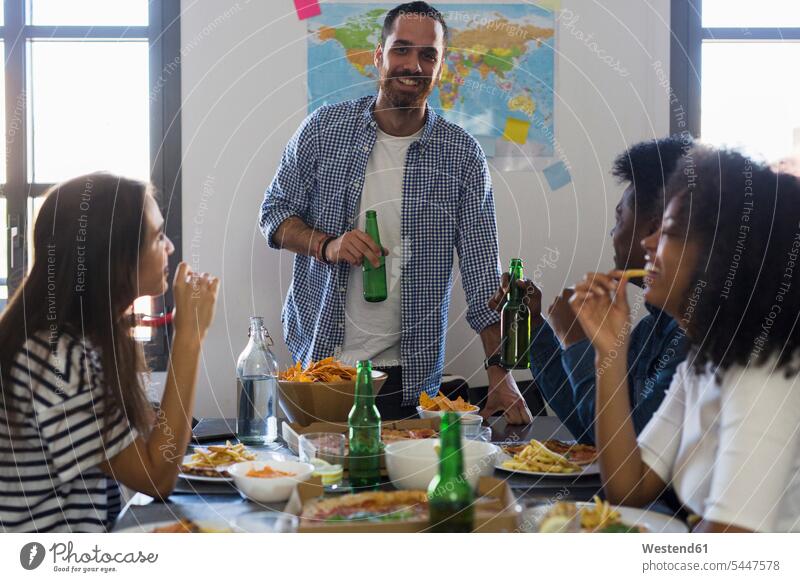 Group of friends socializing with beer and fast food at home Table Tables Beer Beers Ale Pizza Pizzas eating drinking Alcohol alcoholic beverage Alcoholic Drink