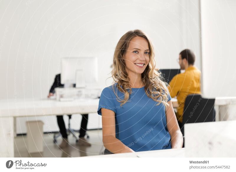Casual businesswoman sitting in office, colleagues working in background caucasian caucasian ethnicity caucasian appearance european copy space businesswomen