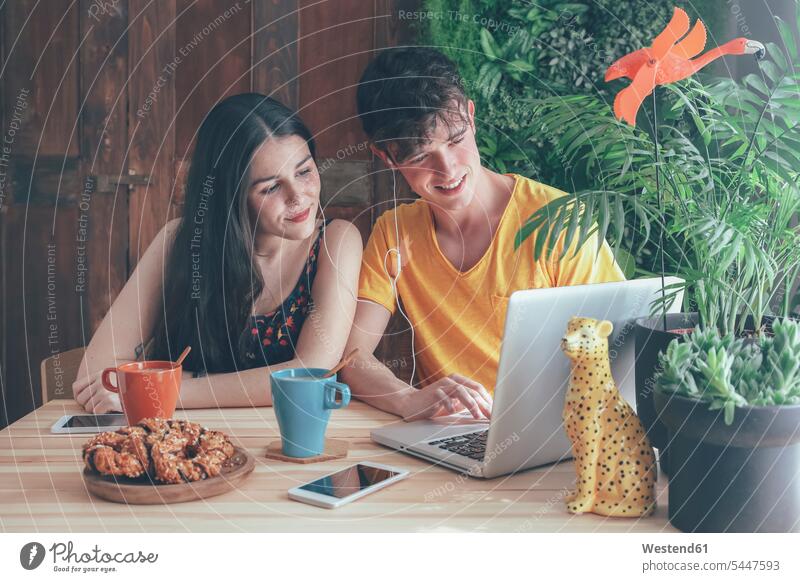 Young couple having coffee and chocolate braids using laptop at home Laptop Computers laptops notebook portrait portraits twosomes partnership couples computer
