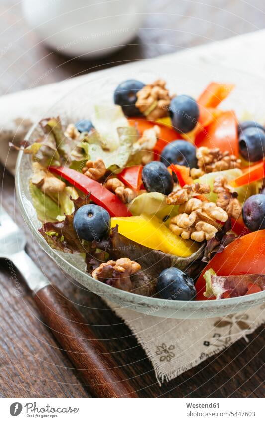Glass bowl of mixed salad with different raw vegetables, blueberries and walnuts Bowl Bowls healthy eating nutrition ingredient ingredients uncooked fruit