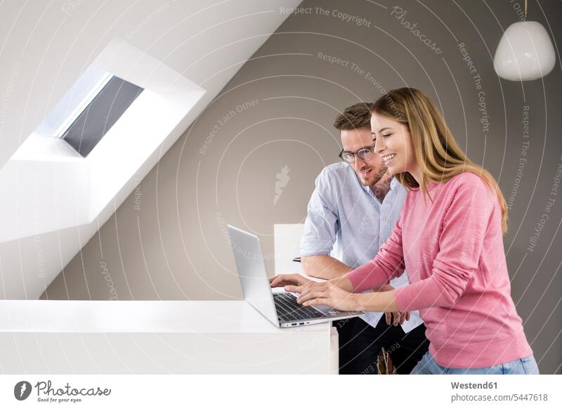 Smiling man and woman sharing laptop Laptop Computers laptops notebook colleagues couple twosomes partnership couples men males females women computer computers