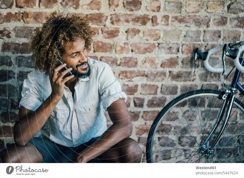 Smiling young man with bicycle on cell phone smiling smile on the phone call telephoning On The Telephone calling bikes bicycles mobile phone mobiles
