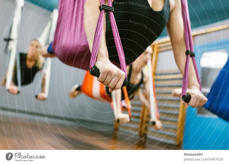 Group of women having a class of aerial yoga exercise exercises exercising training practising woman females mindfulness aware awareness self-care