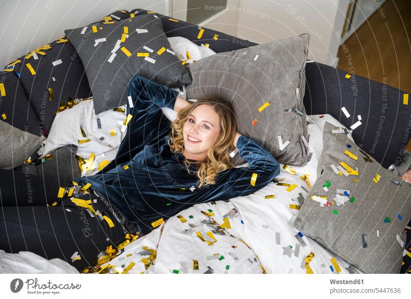 Portrait of laughing young woman lying on bed covered with confetti beds females women Laughter laying down lie lying down portrait portraits paper Adults