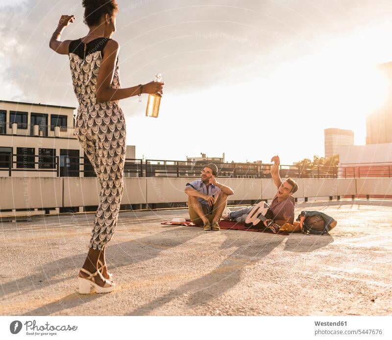 Young woman dancing on a rooftop party friends roof terrace deck dance Fun having fun funny Beer Beers Ale laughing Laughter drinking celebrating celebrate