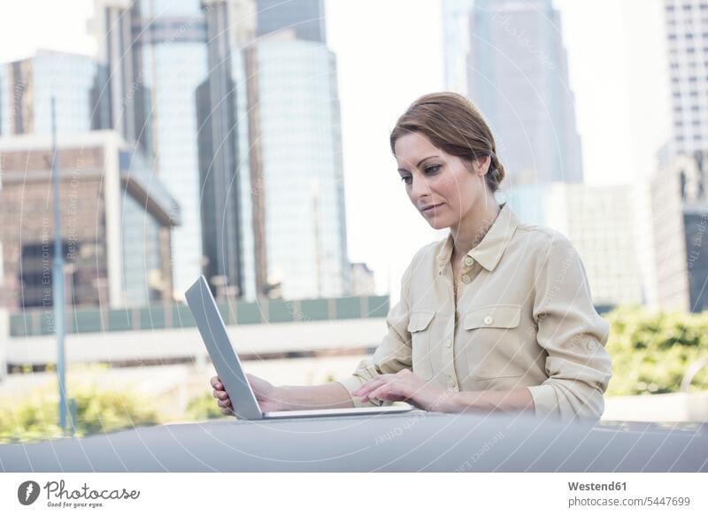 Businesswoman using laptop outdoors businesswoman businesswomen business woman business women Laptop Computers laptops notebook business people businesspeople