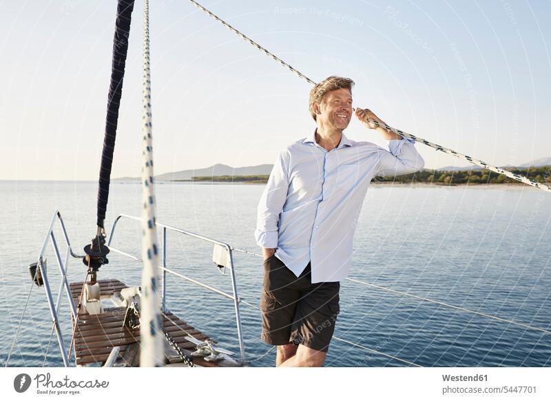 Portrait of smiling mature man on his sailing boat men males Adults grown-ups grownups adult people persons human being humans human beings boat sports standing