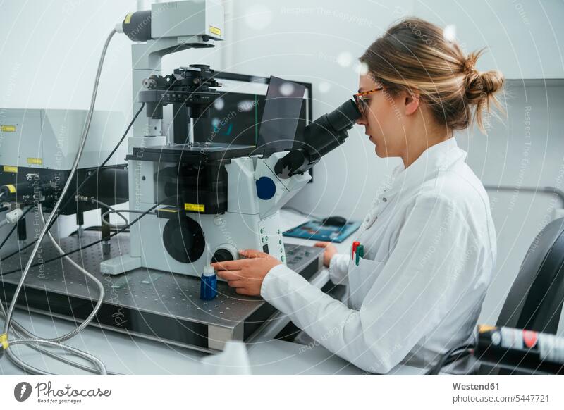 Laboratory technician using microscope in lab examining checking examine laboratory technician woman females women microscopes working At Work examination