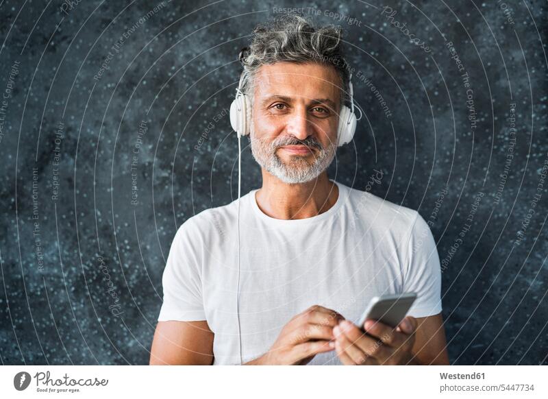 Portrait of a mature man using smartphone, wearing headphones music call telephone call Phone Call mature men on the phone telephoning On The Telephone calling