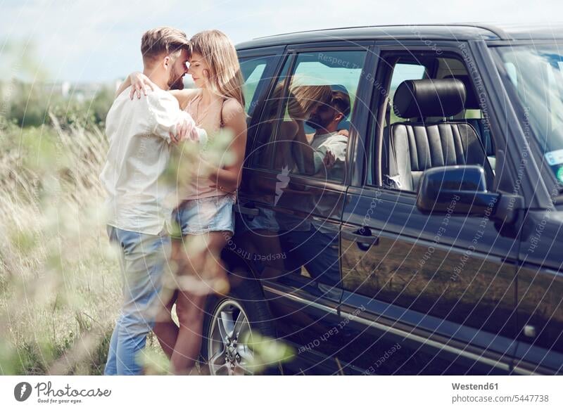 Affectionate young couple outside car automobile Auto cars motorcars Automobiles twosomes partnership couples relaxed relaxation Love loving motor vehicle