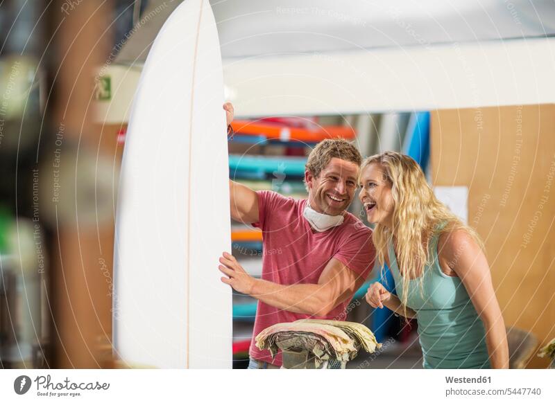 Surfboard shaper workshop, happy man and woman with surfboard laughing Laughter surfboards craft crafts handwork handcraft hand work manual labour manual work