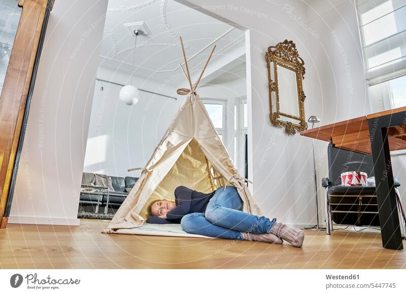 Woman lying in a teepee on the floor laying down lie lying down relaxed relaxation tent tents woman females women relaxing Adults grown-ups grownups adult