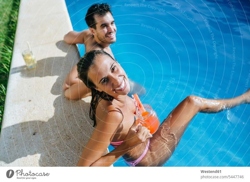 Happy couple in swimming pool with drink at the poolside swimming pools smiling smile happiness happy twosomes partnership couples relaxed relaxation people