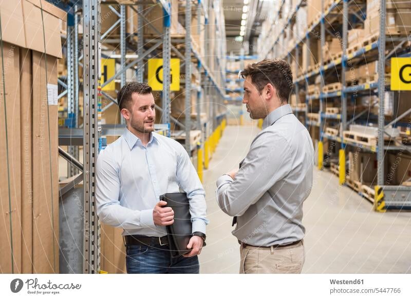 Two men talking in factory warehouse speaking man males working At Work colleagues storehouse storage Adults grown-ups grownups adult people persons human being