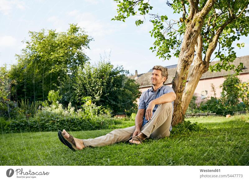 Mature man standing in his garden wearing apron sitting Seated thinking men males leaning home at home daydreaming day dreaming Daydreams Day Dream gardens