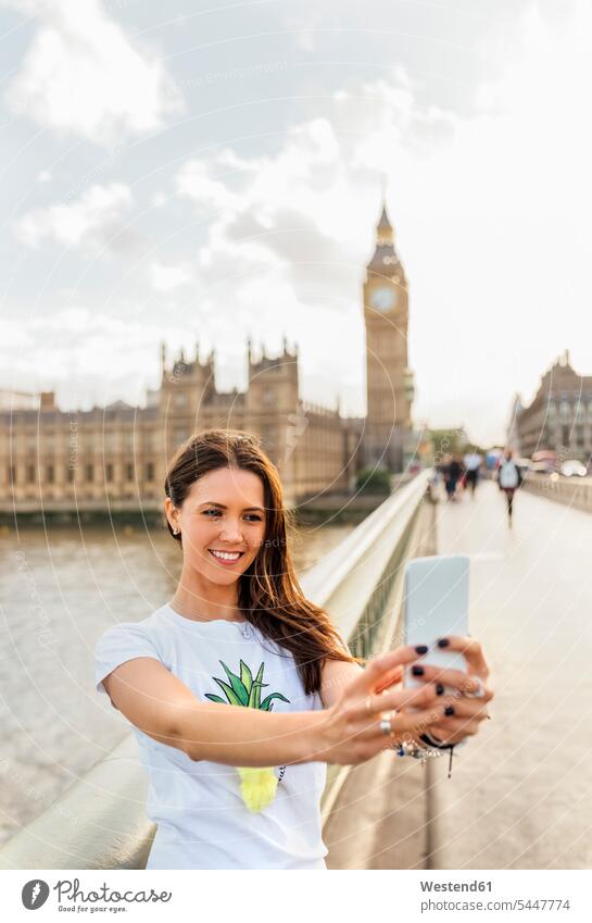 UK, London, beautiful woman taking a selfie on Westminster Bridge Selfie Selfies smiling smile mobile phone mobiles mobile phones Cellphone cell phone