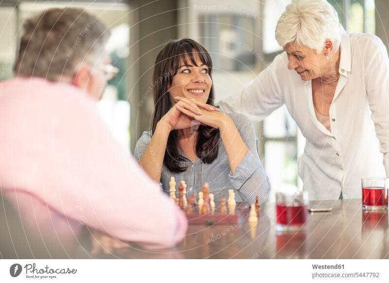 Senior couple playing chess with daughter at home smiling smile twosomes partnership couples senior men senior man elder man elder men senior citizen daughters