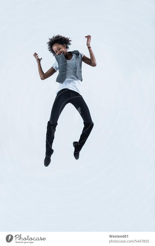 Woman jumping in the air in front of grey background woman females women jump in the air Leaping Adults grown-ups grownups adult people persons human being