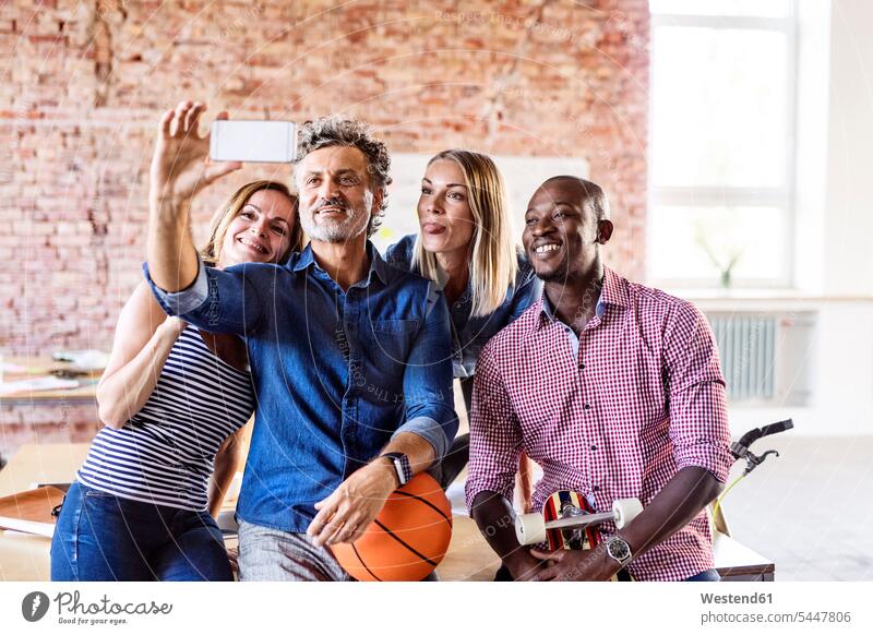 Happy colleagues with basketball in office taking a selfie Selfie Selfies Basketball offices office room office rooms cheerful gaiety Joyous glad Cheerfulness