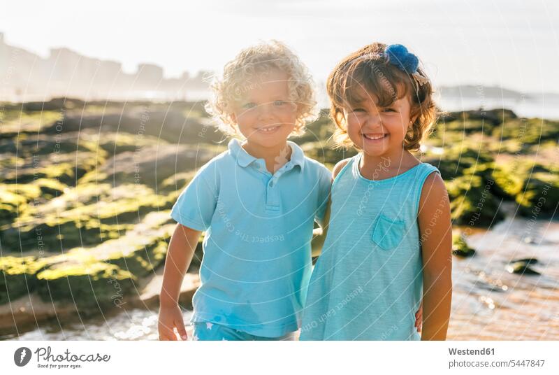Portrait of happy little boy and girl side by side on the beach friends beaches portrait portraits friendship Sea ocean standing smiling smile child children