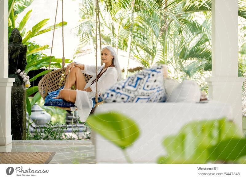Attractive senior woman relaxing in hanging chair sitting Seated senior women elder women elder woman old vacation Holidays attractive beautiful pretty