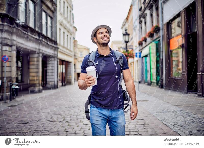 Traveler with backpack walking down city street and holding coffe man men males happiness happy smiling smile Adults grown-ups grownups adult people persons