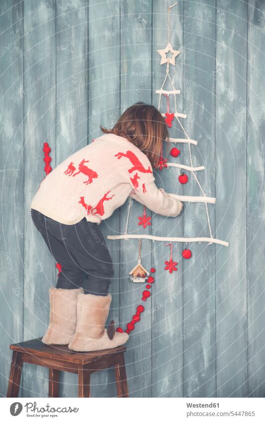 Little girl decorating the wall at Christmas time Christmas decoration Christmas decorations females girls X-Mas yule Xmas X mas celebration Red-Letter Day