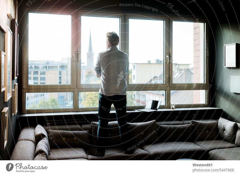 Businessman in lounge area of an office looking out of window Business man Businessmen Business men offices office room office rooms windows view seeing viewing