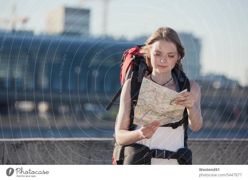 Germany, Berlin, Young woman with backpack looking at map visiting viewing Teenage Girls female teenagers city map city maps Sightseeing backpacker Backpackers