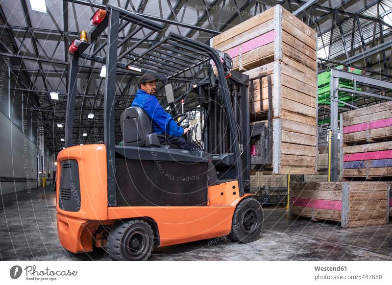 Man on forklift in factory hall storehouse storage warehouse forklifts forklift truck forklift trucks working At Work worker blue collar worker workers