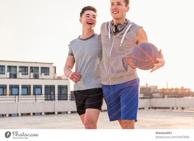 Friends playing basketball at sunset on a rooftop basketballs fit embracing embrace Embracement hug hugging friends mate happiness happy Fun having fun funny